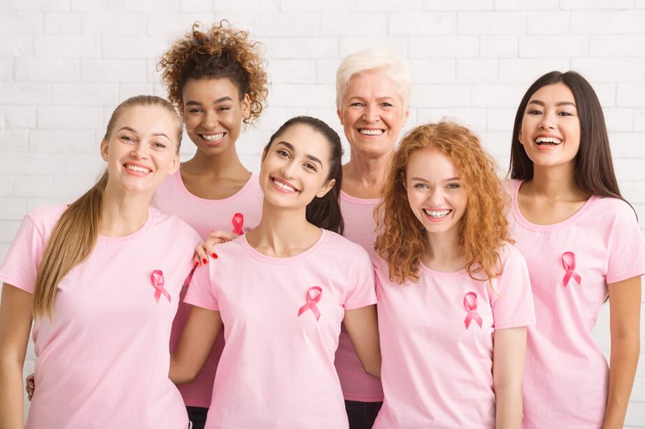A group of women in pink shirts stand close together in support of each other.