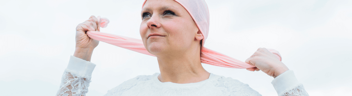 Cancer patient ties a scarf around her head.