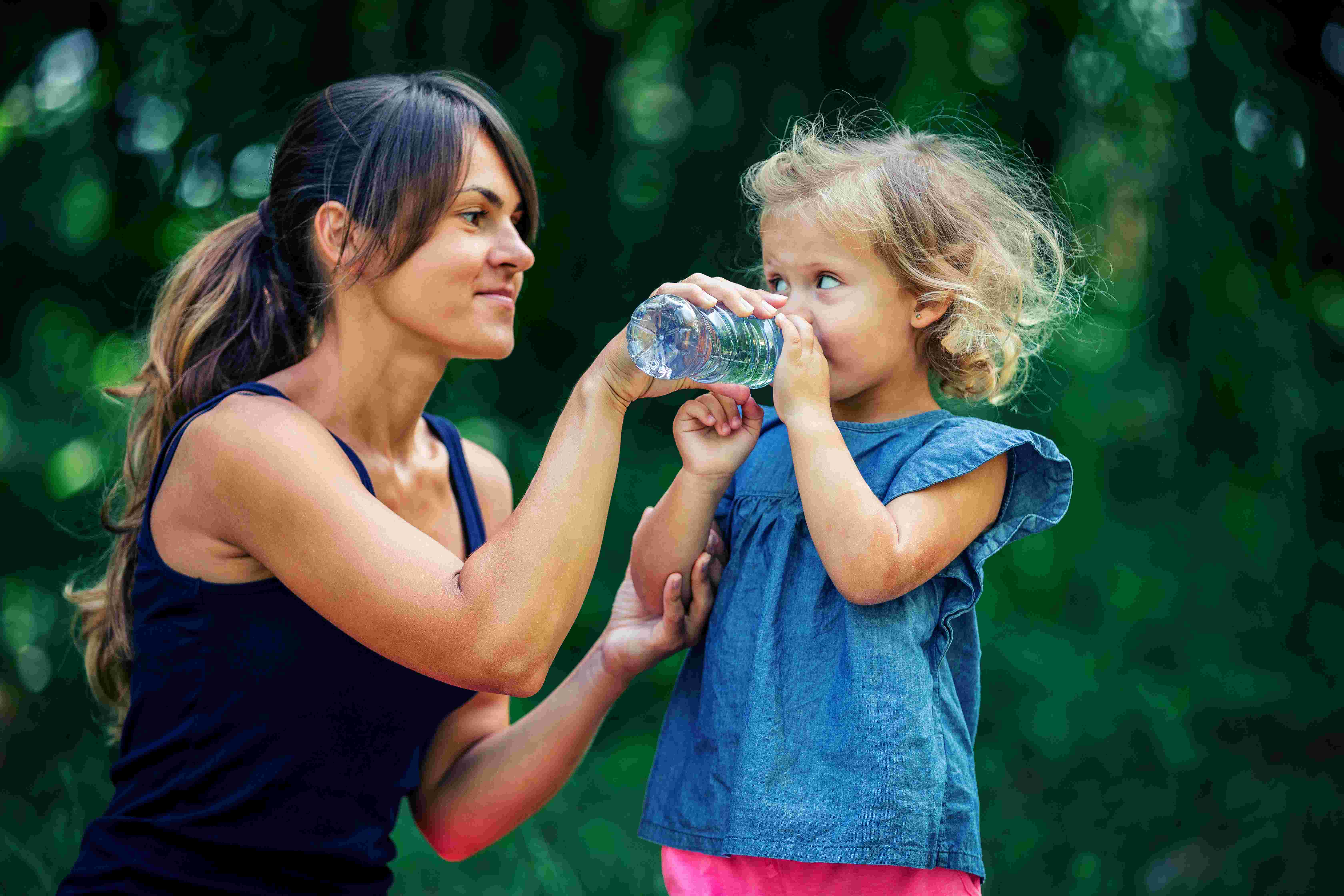 woman gives young girl a drink of water