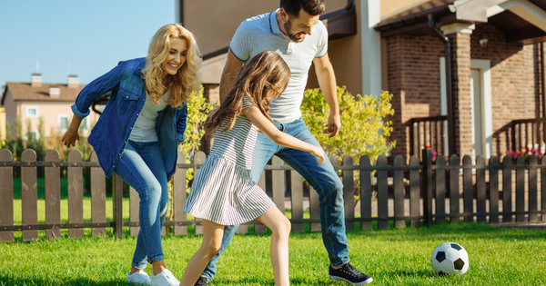 Family playing soccer in their back yard