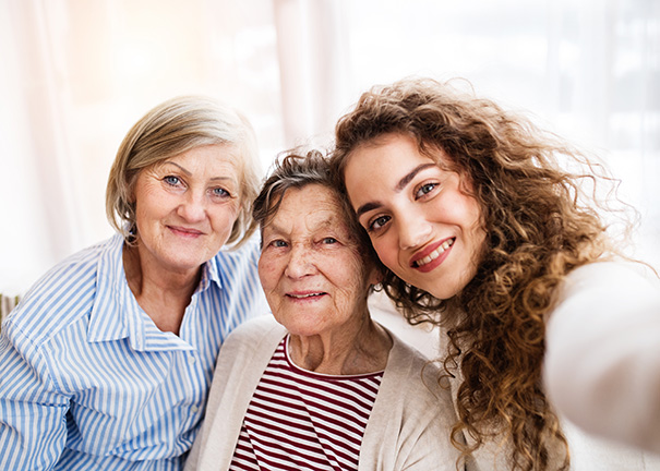 Grandmother, mother and daughter smiling for the camera.