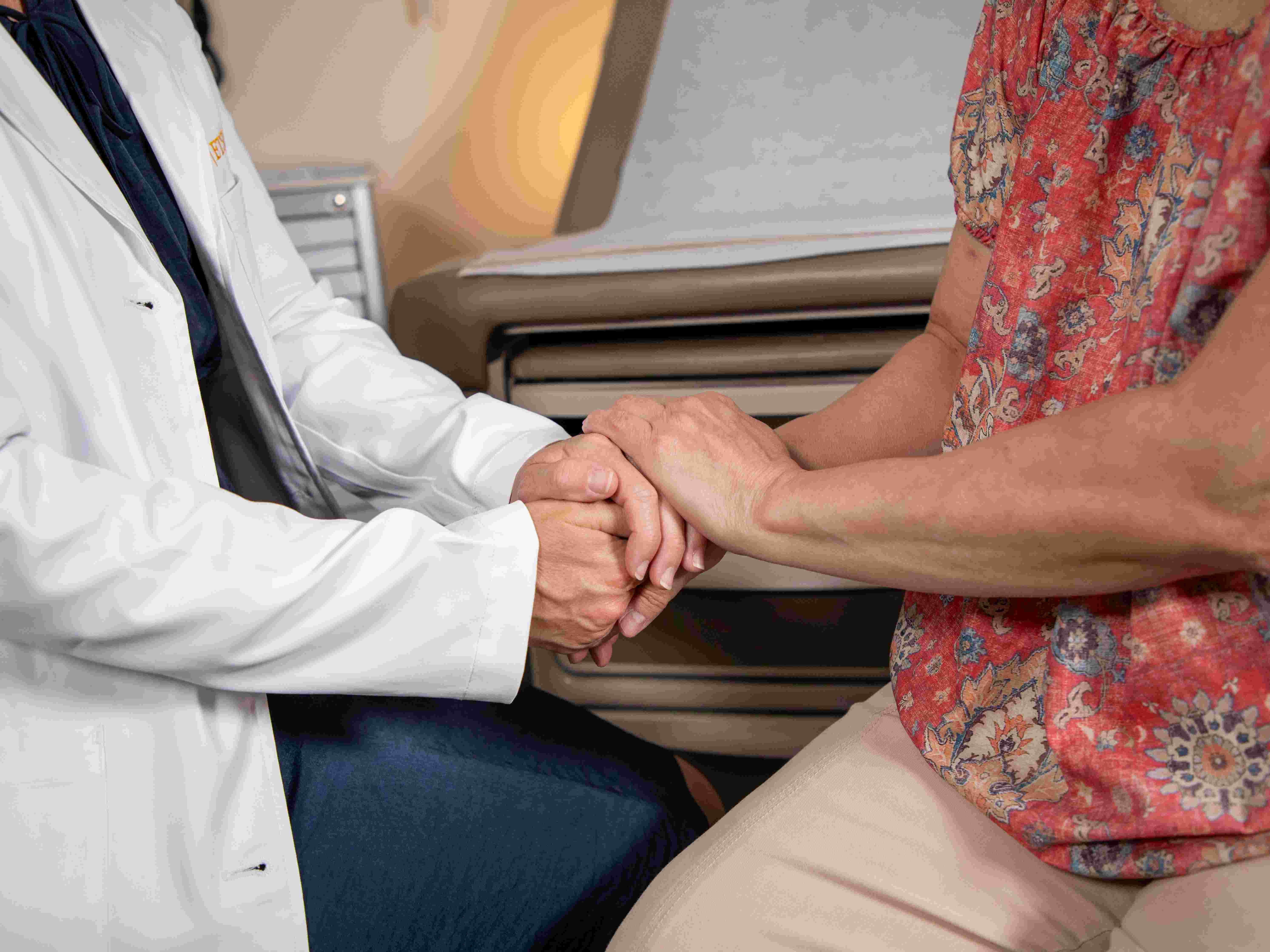  doctor holding patients hands in comforting manner.