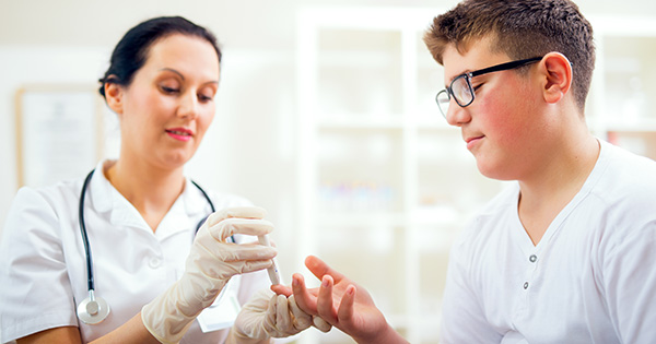 Provider checking pediatric patient's blood sugar.