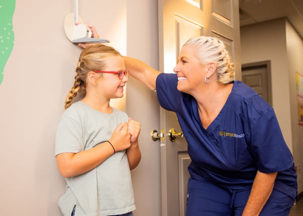 Child getting height measured by nurse in clinic.
