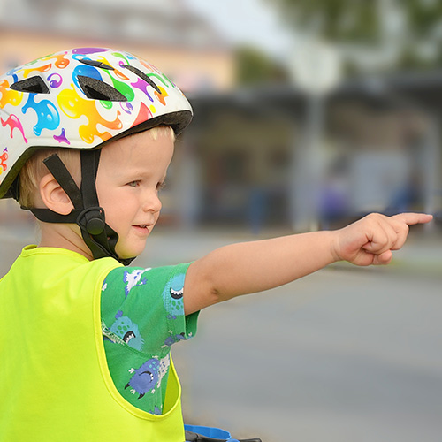 Child dressed in bright colors wearing bike helmet.