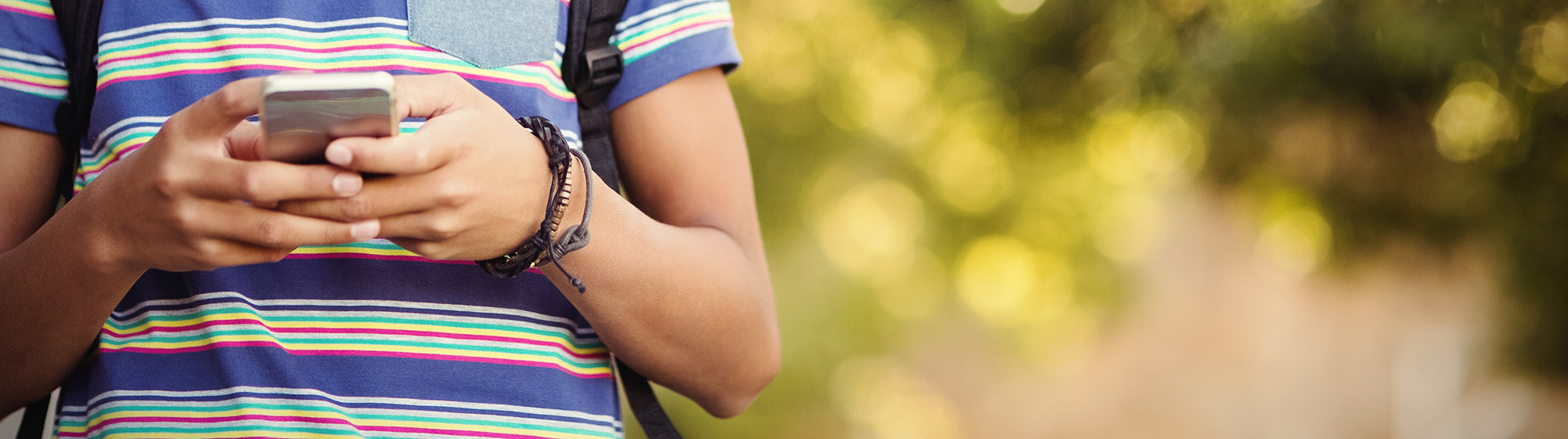 Teenager's hands holding a cell phone.