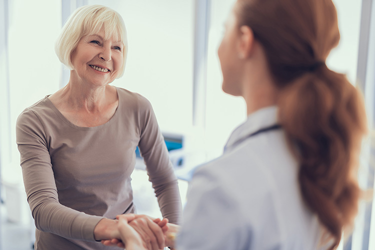 Provider holding smiling patients hand in a clinic.